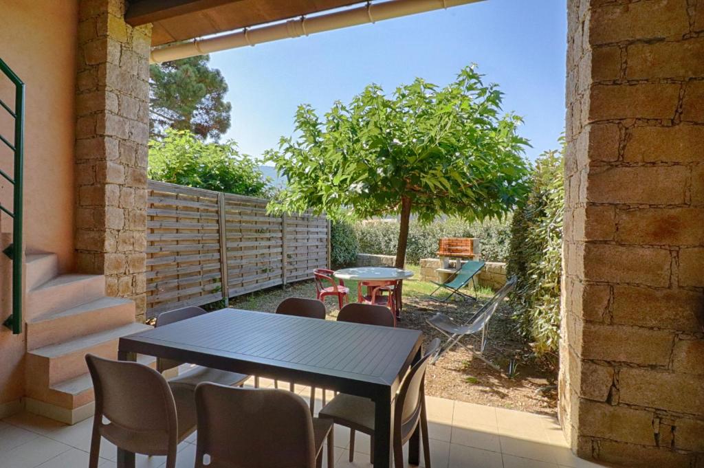d'une terrasse avec une table, des chaises et un arbre. dans l'établissement Appartement n1 rez de jardin LA LISCIA, à Calcatoggio