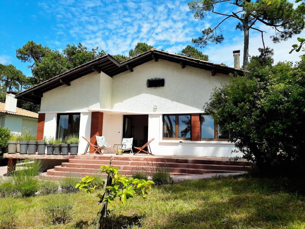 ein weißes Haus mit zwei Stühlen auf der Veranda in der Unterkunft PINSONS maison familiale proche plage in Pyla-sur-Mer