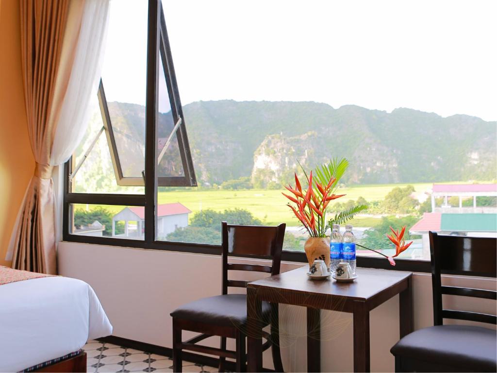 um quarto com uma cama e uma mesa com cadeiras e uma janela em Tam Coc Lion Kings Hotel & Resort em Ninh Binh