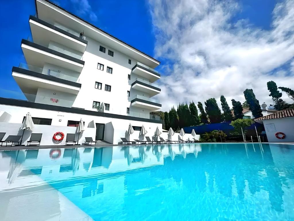 un hotel con piscina frente a un edificio en Modern Oasis - Pool, Gym & Tennis, en Puerto de la Cruz