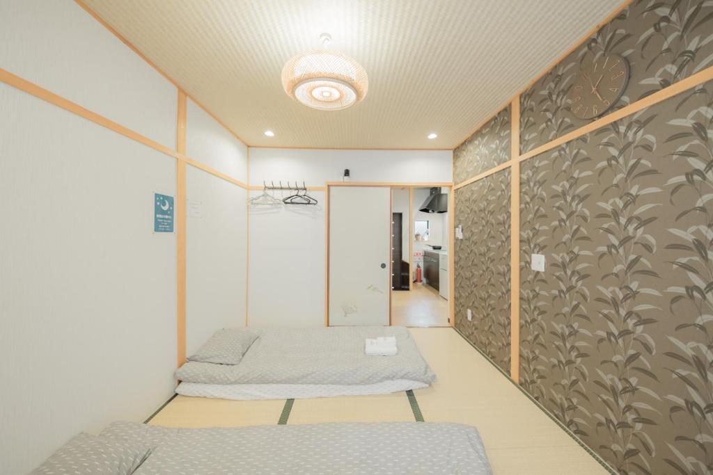 een kamer met 2 bedden en een muur bij CandyHouse鹤桥站徒步7分钟难波日本桥心斋桥8分钟奈良usj天王寺直达 in Osaka
