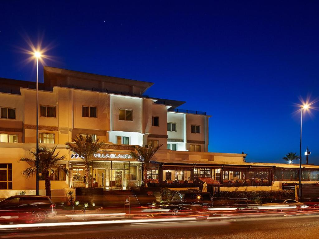 Villa Blanca Urban Hotel في الدار البيضاء: مبنى في الليل مع سيارات تمر عليه