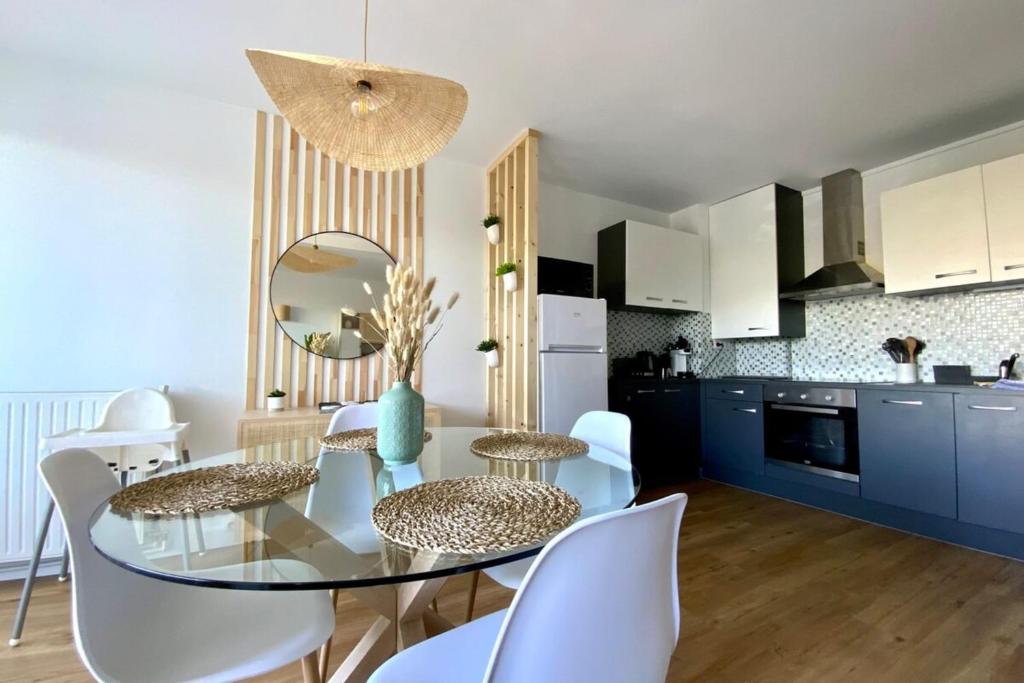 a kitchen and dining room with a glass table and white chairs at Lensoleillée - Proche port et climatisé ! in Mauguio