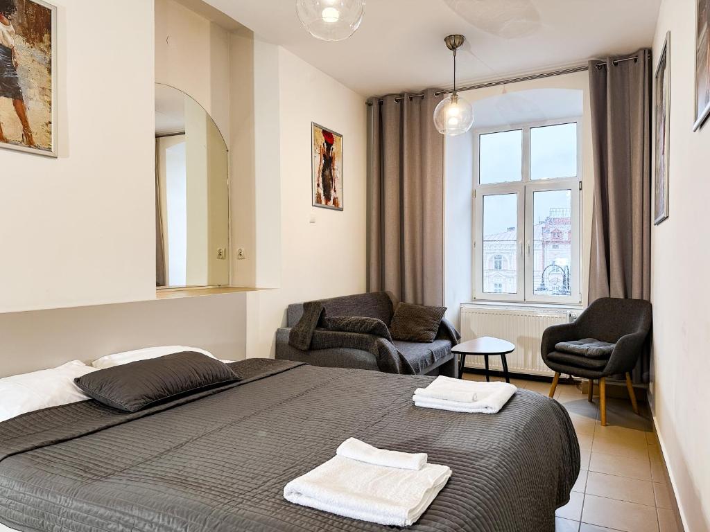 1 dormitorio con 1 cama, 2 sillas y ventana en Noclegi Rynek14 Przemyśl Old Town View, en Przemyśl