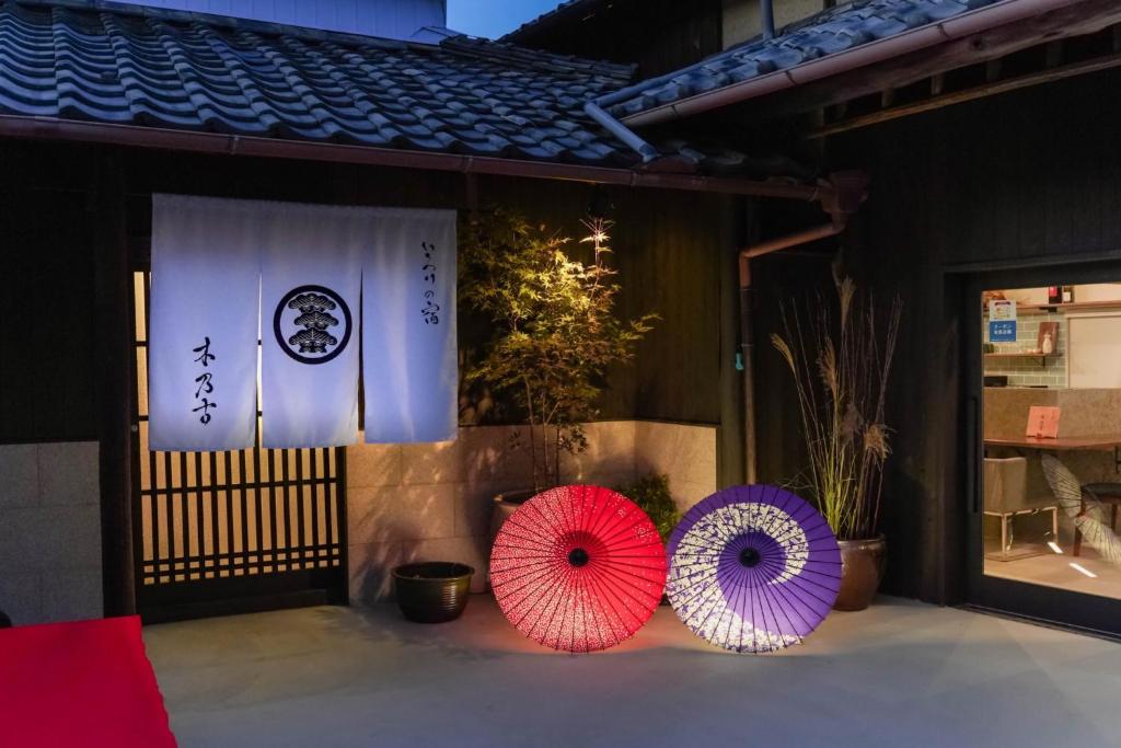 zwei rote und violette Regenschirme vor einem Gebäude in der Unterkunft Irori no Yado Kinoko - Vacation STAY 76611v in Sakaide