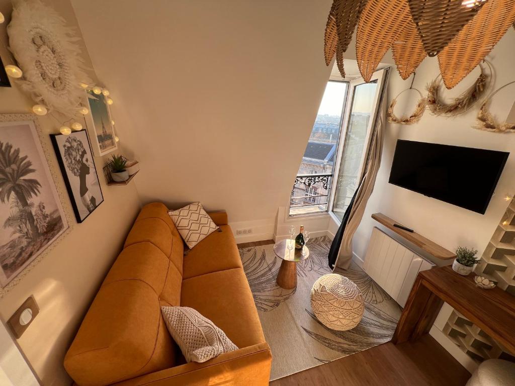 a living room with a couch and a television at Rooms with fabulous view on Paris roofs in Paris