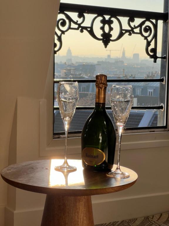 a bottle of wine on a table with two glasses at Rooms with fabulous view on Paris roofs in Paris