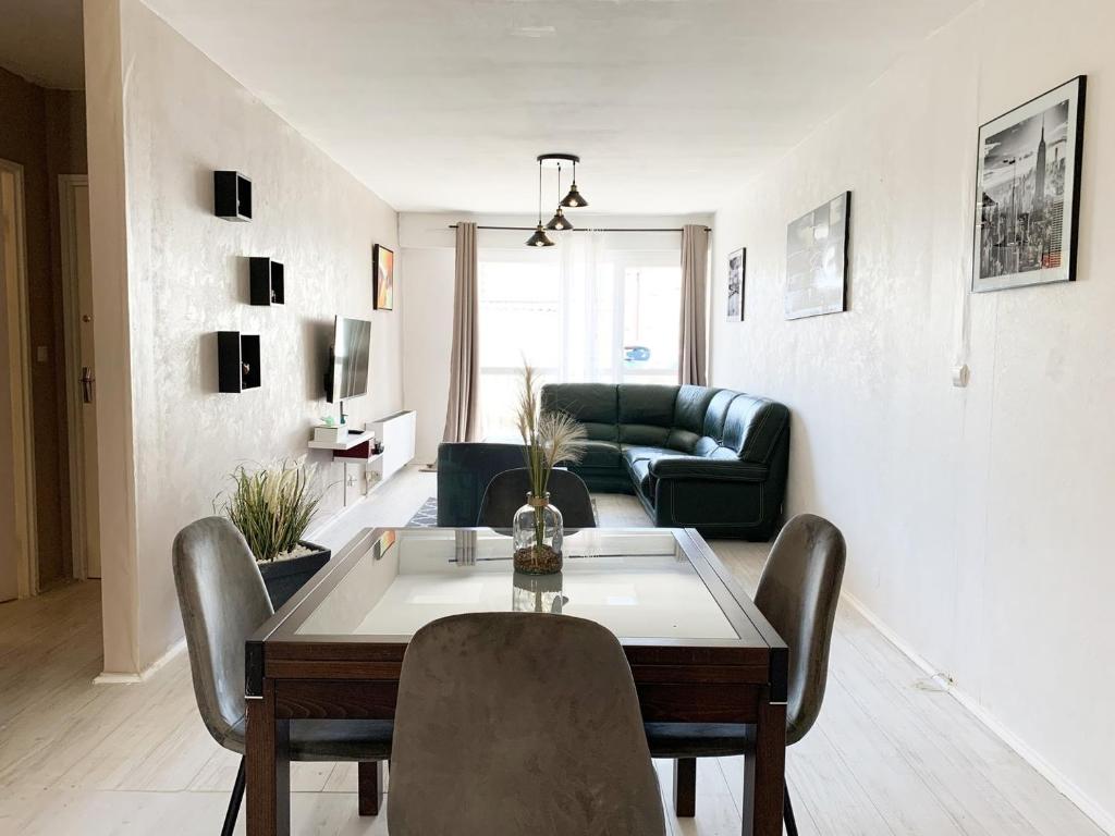 a living room with a table and a couch at Le Mainvillois - Parking Included in Mainvilliers