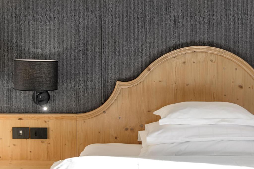 a bedroom with a bed with a wooden headboard at Bio Hotel Hermitage in Madonna di Campiglio