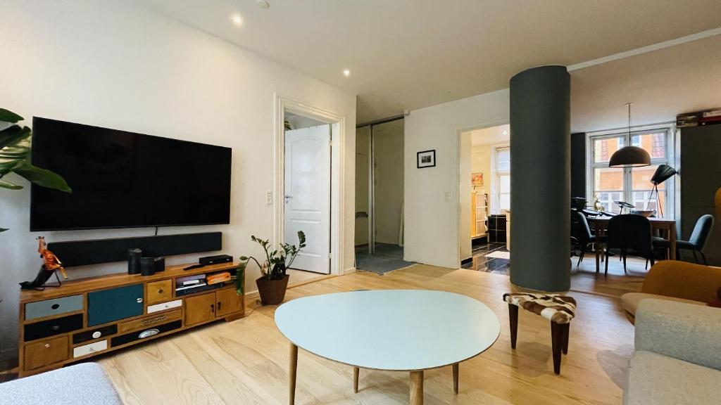 un soggiorno con TV a schermo piatto e tavolo di ApartmentInCopenhagen Apartment 1580 a Copenaghen