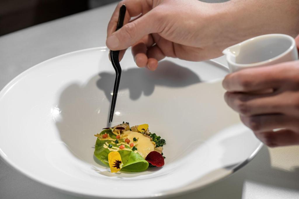 a person eating a plate of food with a fork at Bio Hotel Hermitage in Madonna di Campiglio