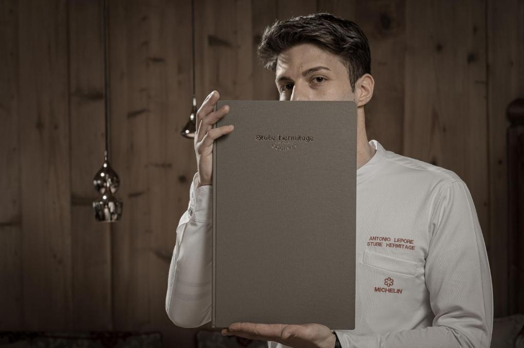 a man in an apron holding a box at Bio Hotel Hermitage in Madonna di Campiglio