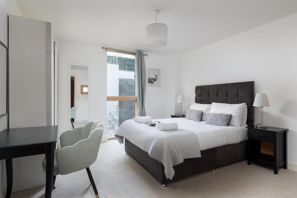 1 dormitorio con 1 cama grande, escritorio y ventana en City Stay Apartments - Vizion, en Milton Keynes