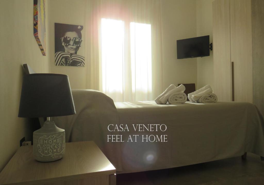 a bed in a room with a table with a lamp at Casa Veneto in Mazara del Vallo