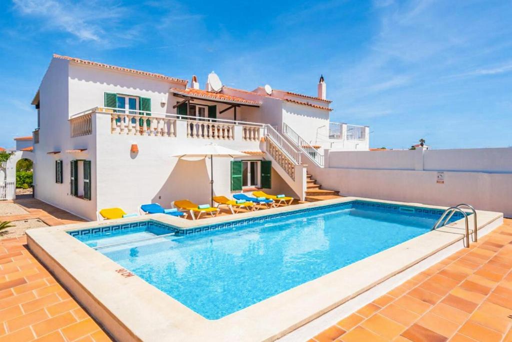 uma villa com piscina em frente a uma casa em Villa Miguels em Es Mercadal