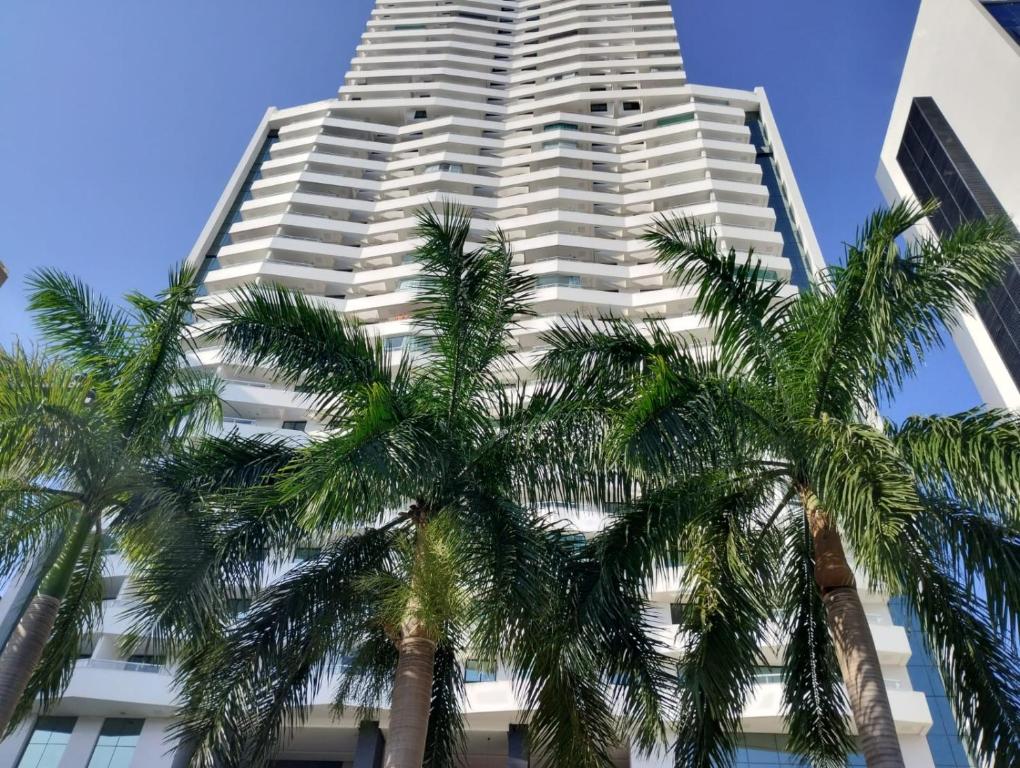 un edificio alto con palmeras delante en Mondial Apartments By BnbHost en Salvador