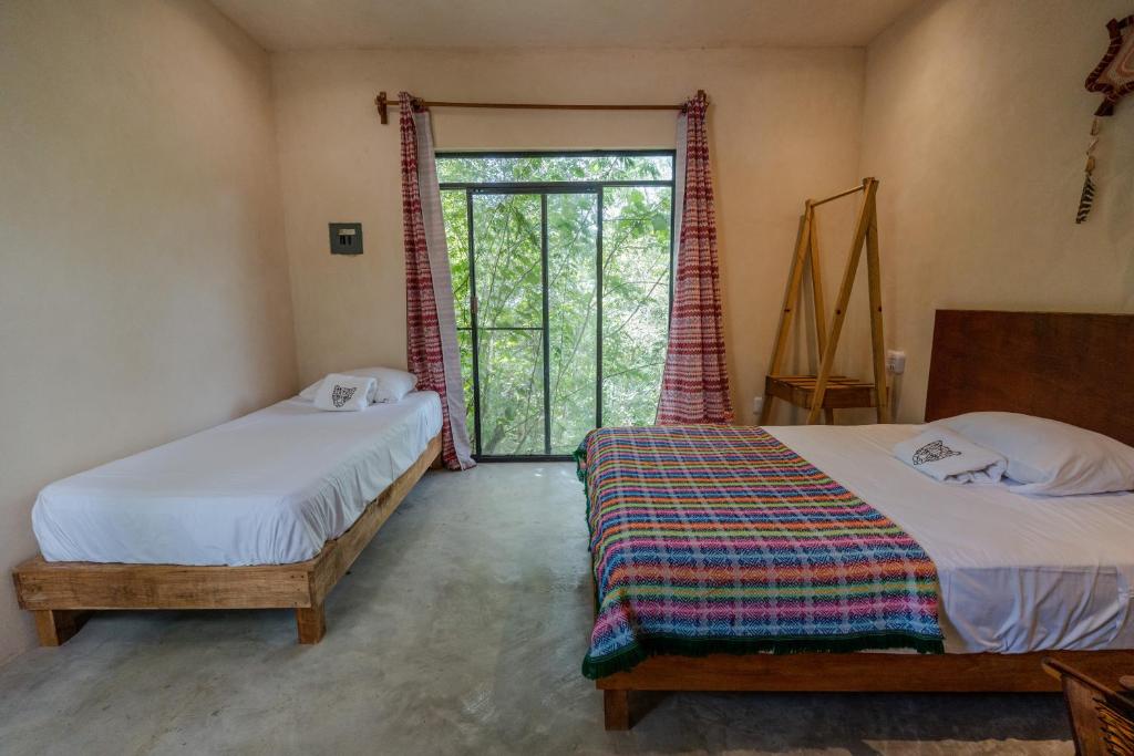 a bedroom with two beds and a sliding glass door at Aldea Jaguar in Francisco Uh May