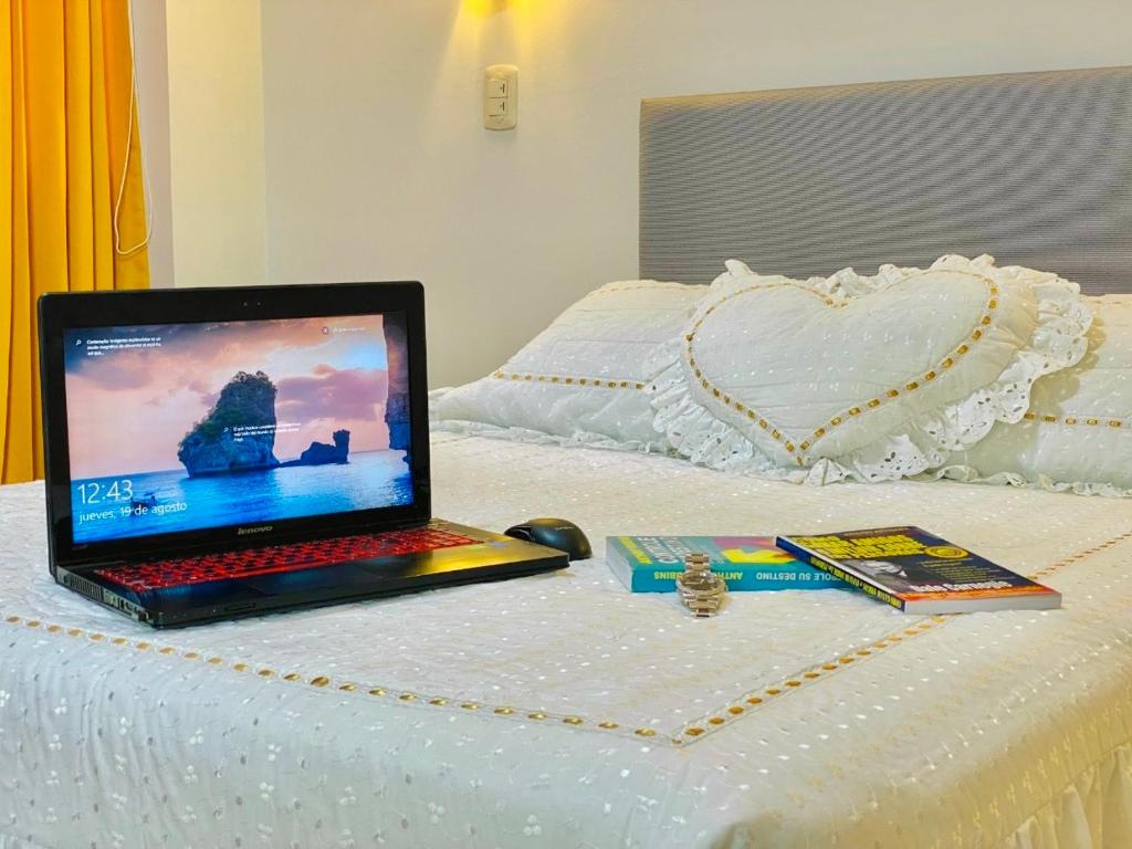 un ordenador portátil sentado en la parte superior de una cama en Jultom Inn Hotel & Suites, en Trujillo