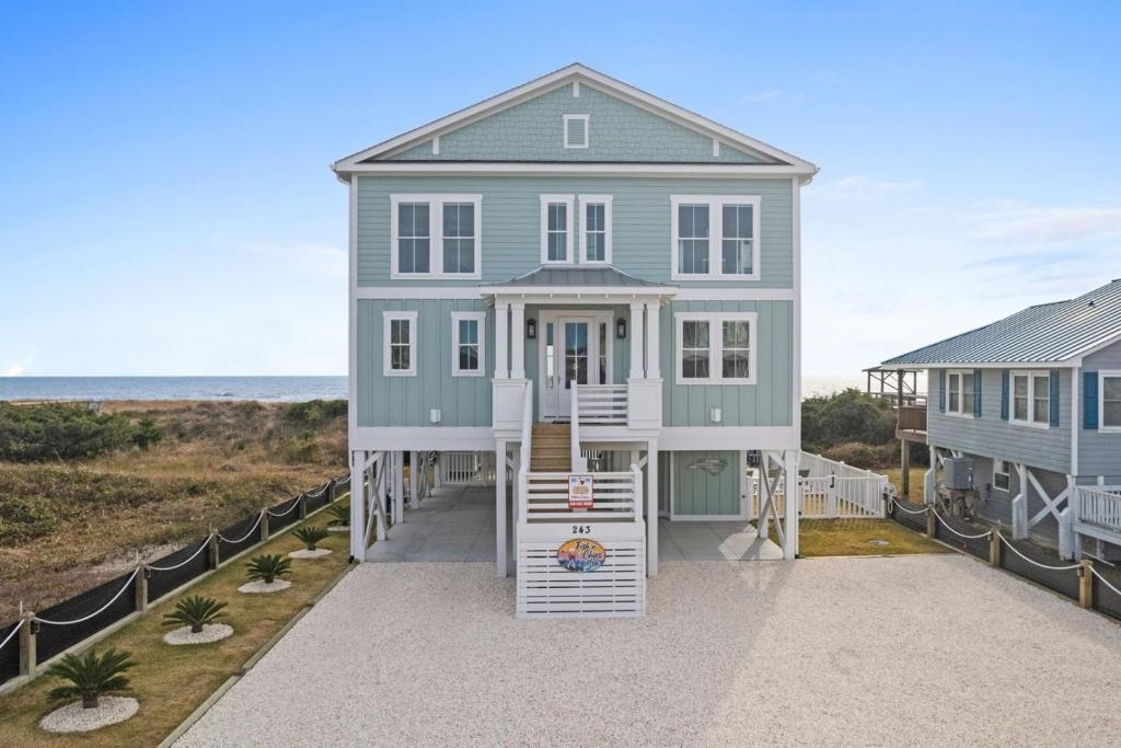 a house on the beach with the ocean in the background at Fish-N-Chips by the Sea home in Holden Beach
