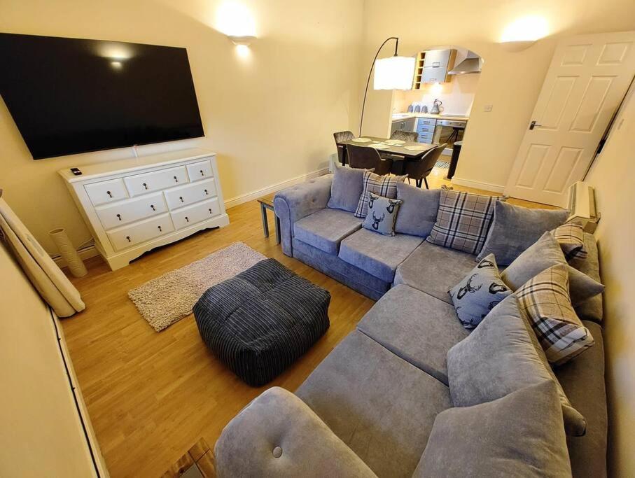 a living room with a couch and a flat screen tv at Cosy Central Modern Apartment in Nantwich