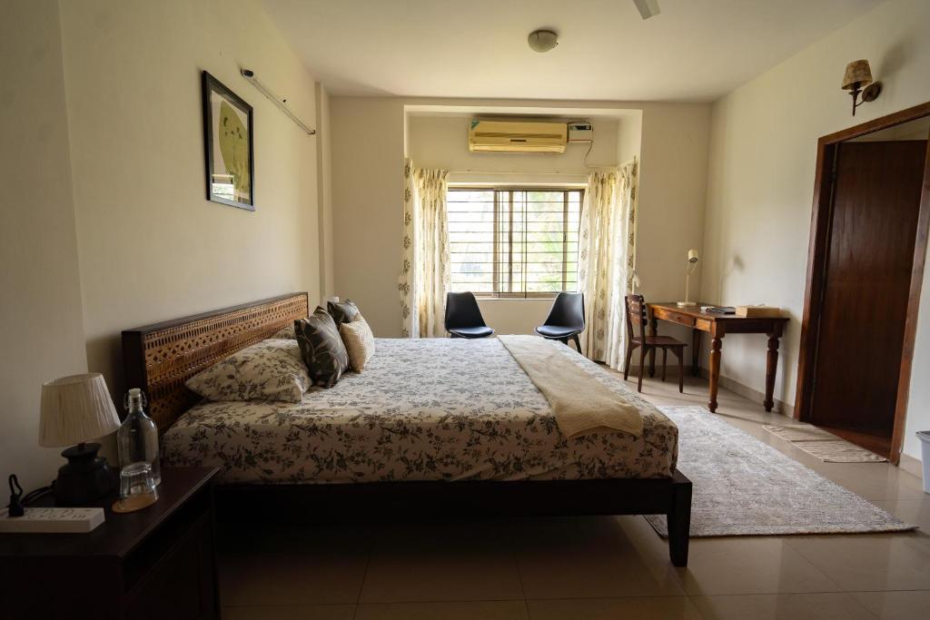a bedroom with a bed and a desk and a window at Luho 306 in Bangalore