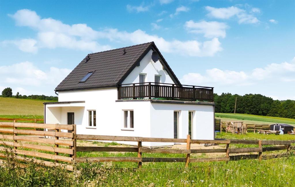 une maison blanche avec un toit noir dans un champ dans l'établissement Beautiful Home In Sucha Huta With Kitchen, 