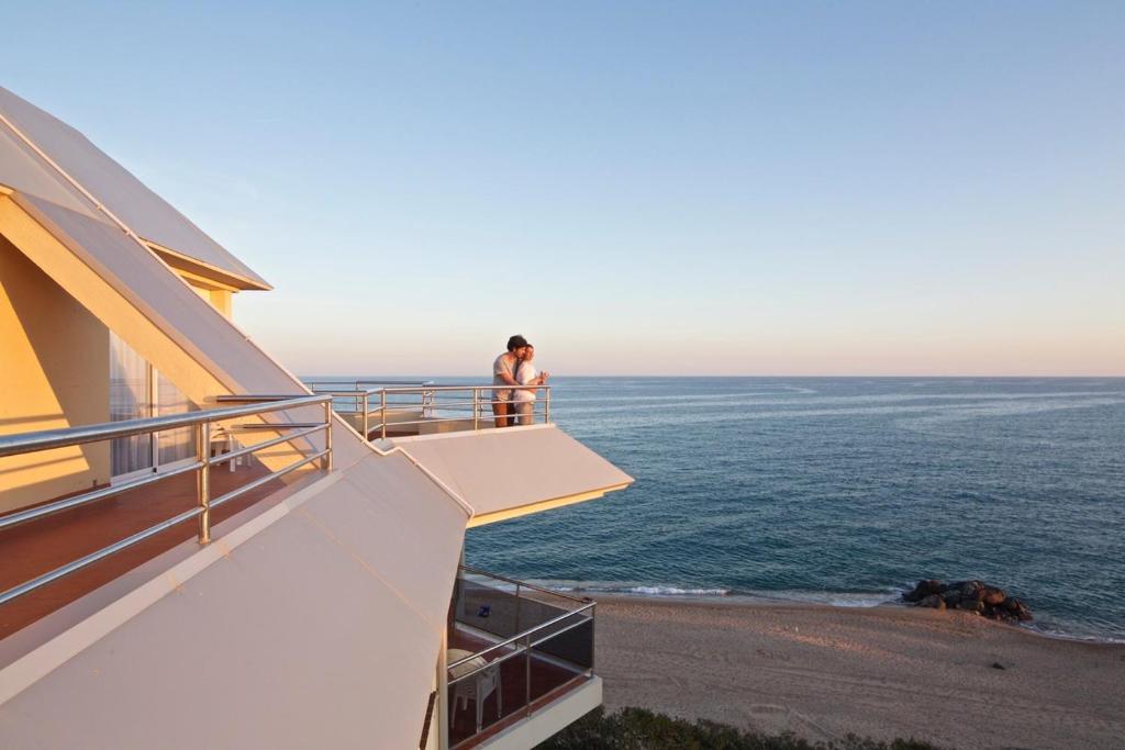 una persona parada en un balcón con vistas al océano en Apartamentos Bon Repós, en Santa Susanna