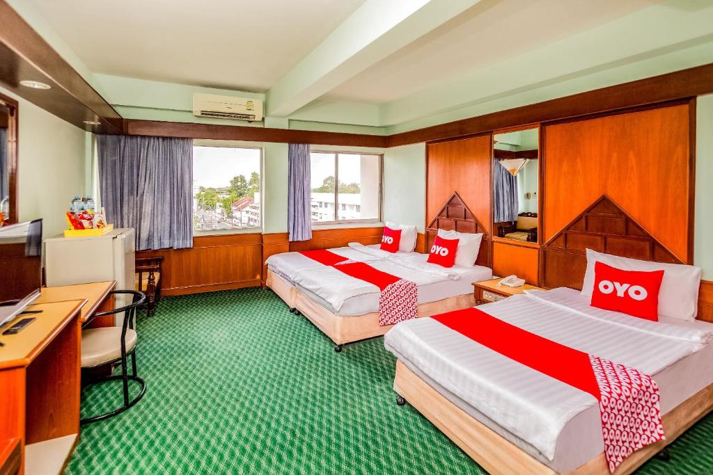 een hotelkamer met 2 bedden en een bureau bij OYO 441 Grand Thara Hotel in Suratthani