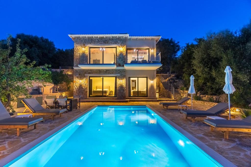 a villa with a swimming pool in front of a house at Aloni Villas Sea View in Katouna
