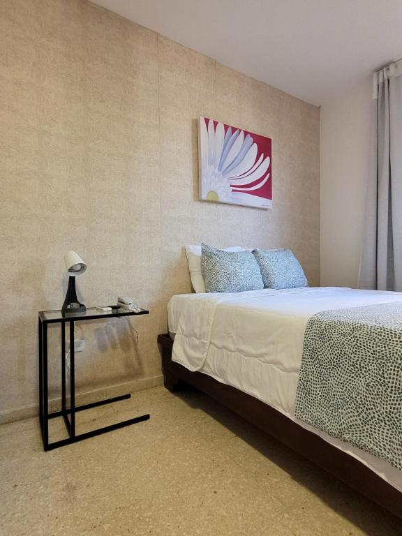 um quarto com uma cama e uma mesa lateral em Aparta Hotel Drake Piantini em Santo Domingo