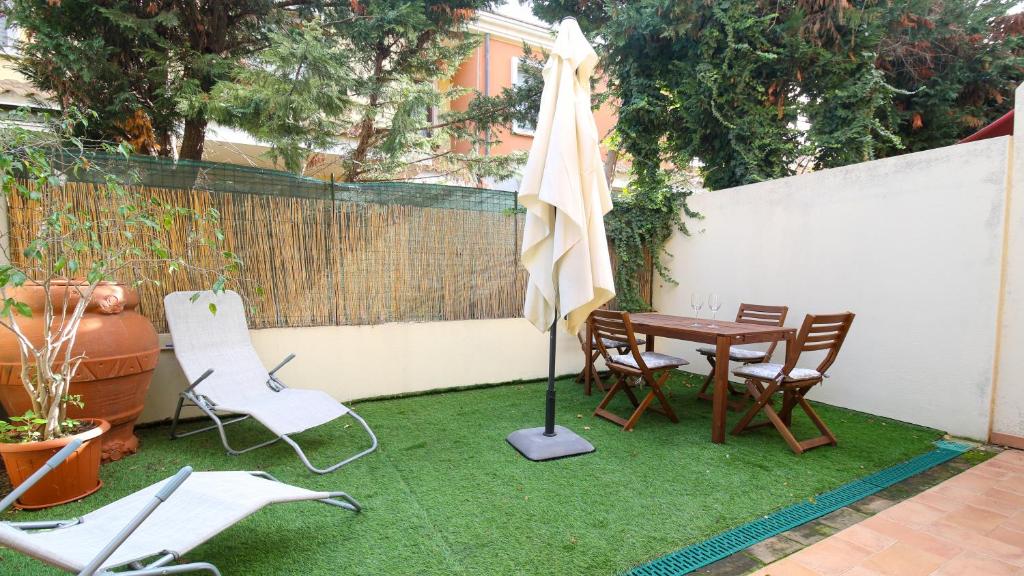 patio con tavolo, sedie e ombrellone di Welcomely - Villino Octagon a Elmas