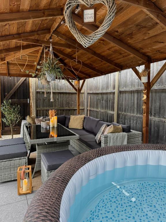 a patio with a couch and a table and a pool at Barn with Hot Tub in Goffs Oak