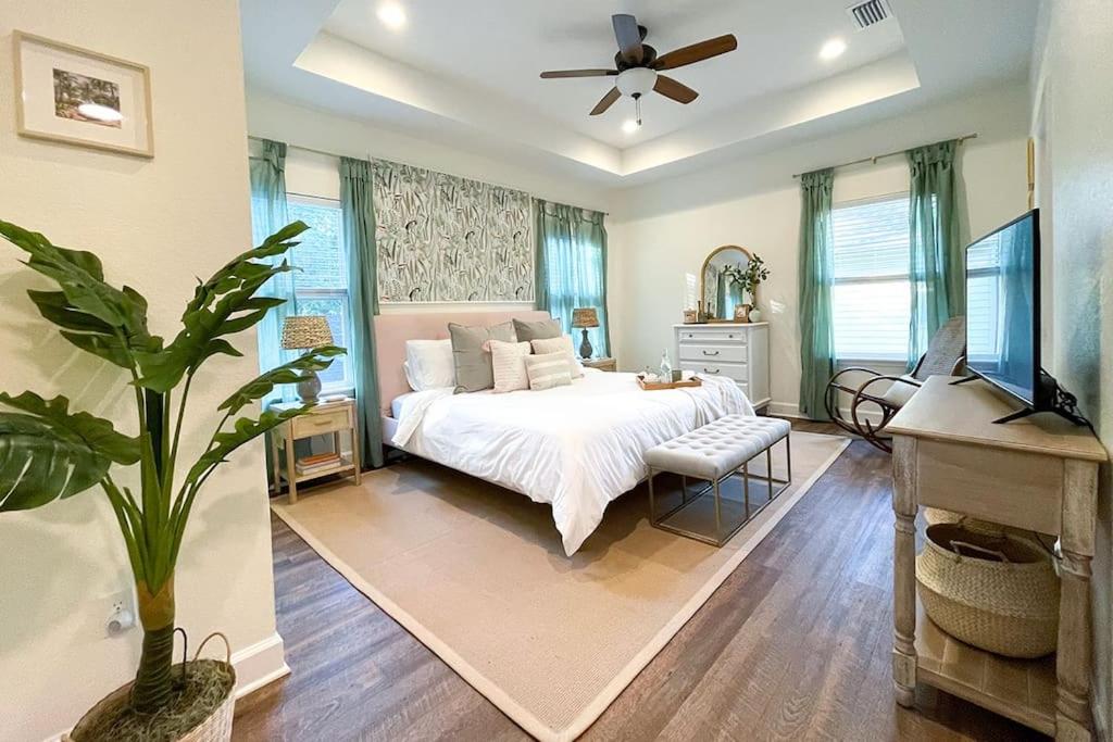 1 dormitorio con cama blanca y ventilador de techo en The Floridian Newly Built Dreamhome Central, en Gainesville