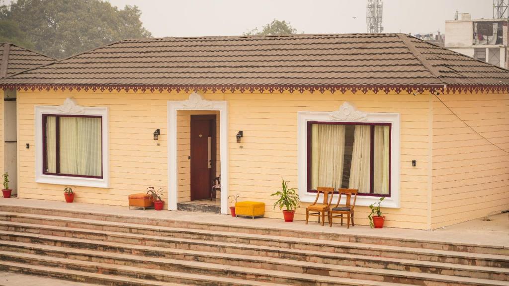 una piccola casa gialla con tavolo e sedia di Ayodhya haat Luxury Cottages a Ayodhya