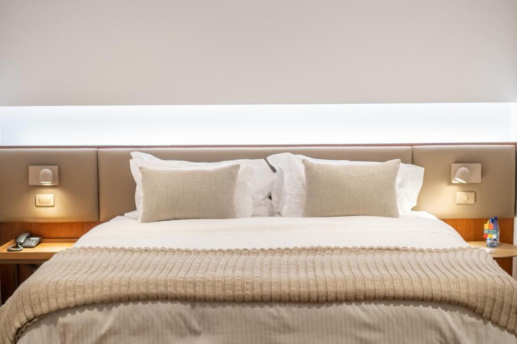una camera da letto con un grande letto con lenzuola e cuscini bianchi di Quality Hotel Pampulha & Convention Center a Belo Horizonte