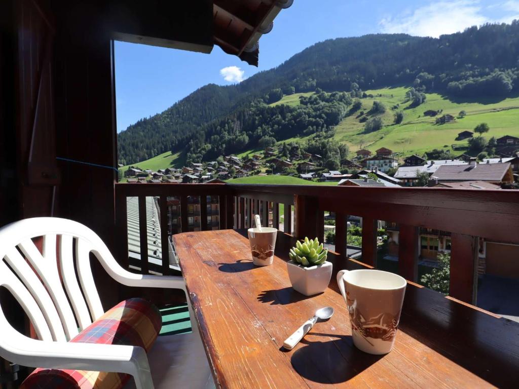 d'une table en bois sur un balcon avec vue sur la montagne. dans l'établissement Duplex 6 Pers à Arêches-Beaufort : Piscine, Garage, Proche Ski, Animaux OK, Wifi - FR-1-342-255, à Beaufort