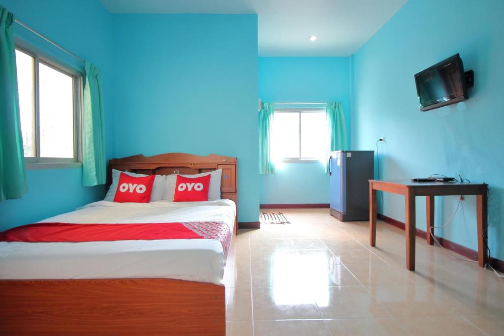 a bedroom with blue walls and a bed with red pillows at OYO 496 Chok Phikul Thong Resort in Nakhon Pathom