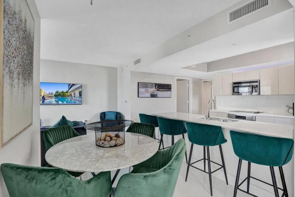 a kitchen with a table and some green chairs at Gorgeous 4 Bedroom Condo Pool and Stunning Views in Hallandale Beach