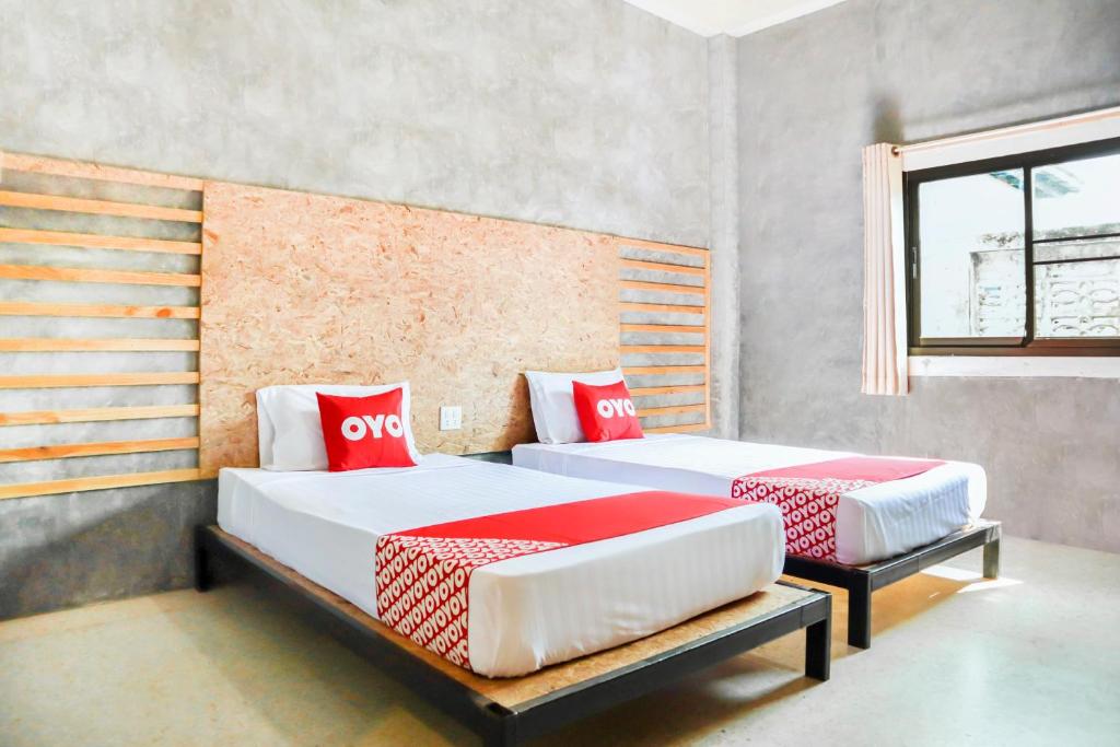2 camas en una habitación con almohadas rojas y blancas en OYO 674 Greenery Home, en Ban Nam Sai