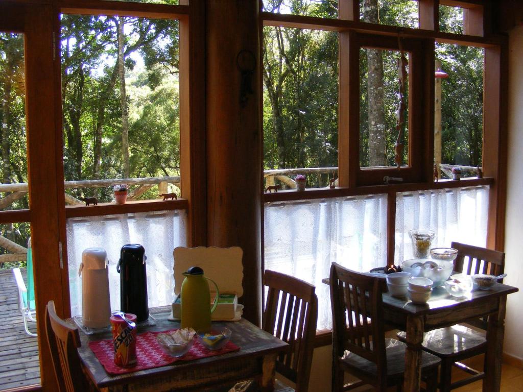 d'une salle à manger avec une table, des chaises et des fenêtres. dans l'établissement Nas Nuvens Hospedaria, à Monte Verde