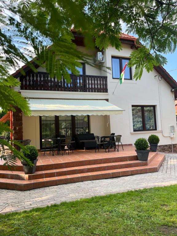 a house with a patio with tables and chairs at Aventurin House *** in Révfülöp