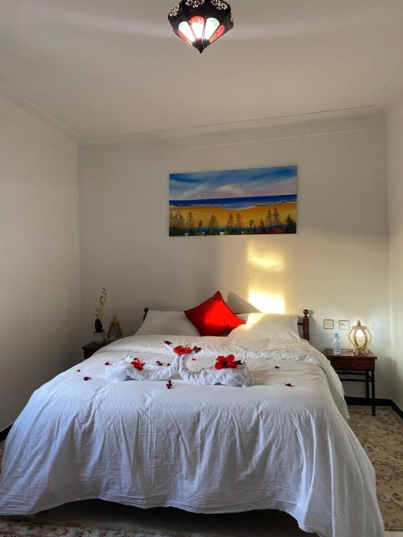 una camera da letto con un letto bianco con fiori rossi di Latifa house a Oualidia