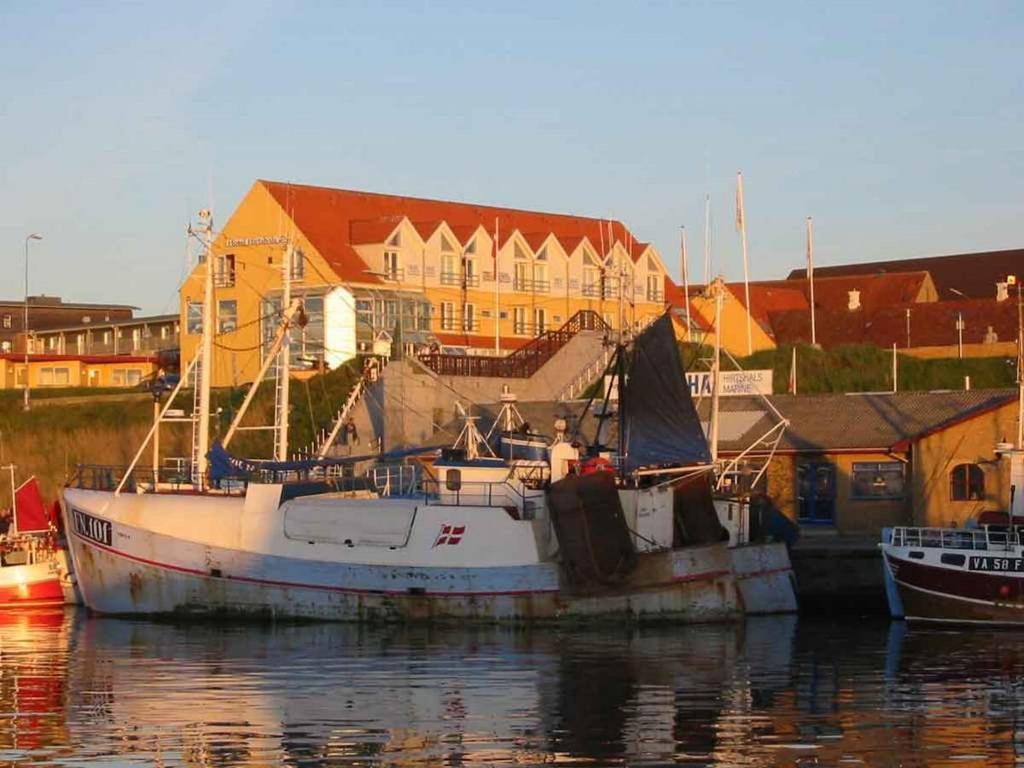 a small boat is docked in a harbor at Hotel Hirtshals in Hirtshals