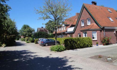 a house with a car parked in the driveway at Hotel Pension Friesenruh in Bensersiel