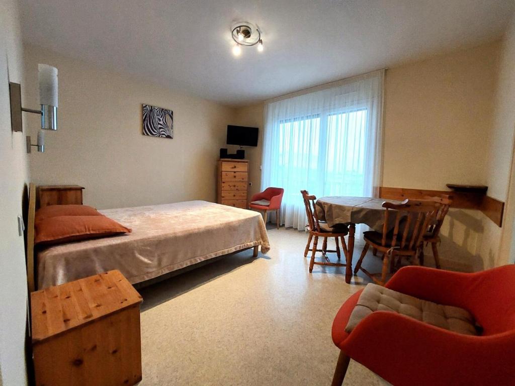 une chambre avec un lit, une table et des chaises dans l'établissement Résidence Montcalm D - Mignon logement, très agréable avec piscine, tennis ! MAE-6794, à Aix-les-Bains