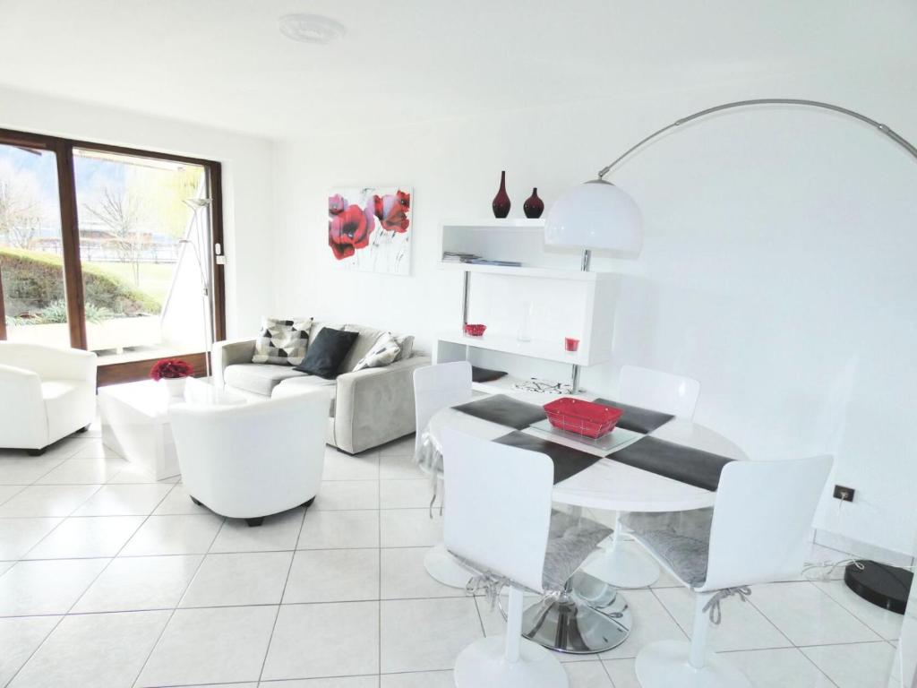 - un salon blanc avec une table et des chaises blanches dans l'établissement Résidence Les Colverts - Moderne et lumineux avec belle vue sur le lac ! MAE-7274, à Aix-les-Bains