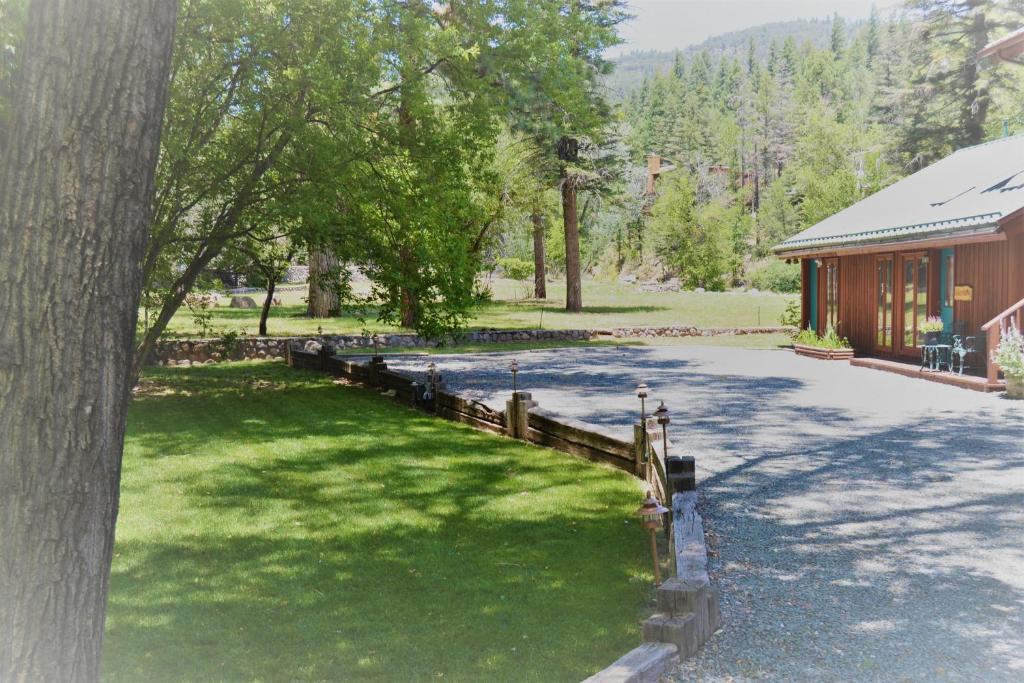 a building with a fence next to a grass yard at River Hideout: One Bedroom Duplex Cottage ON THE RIVER!! in Ruidoso