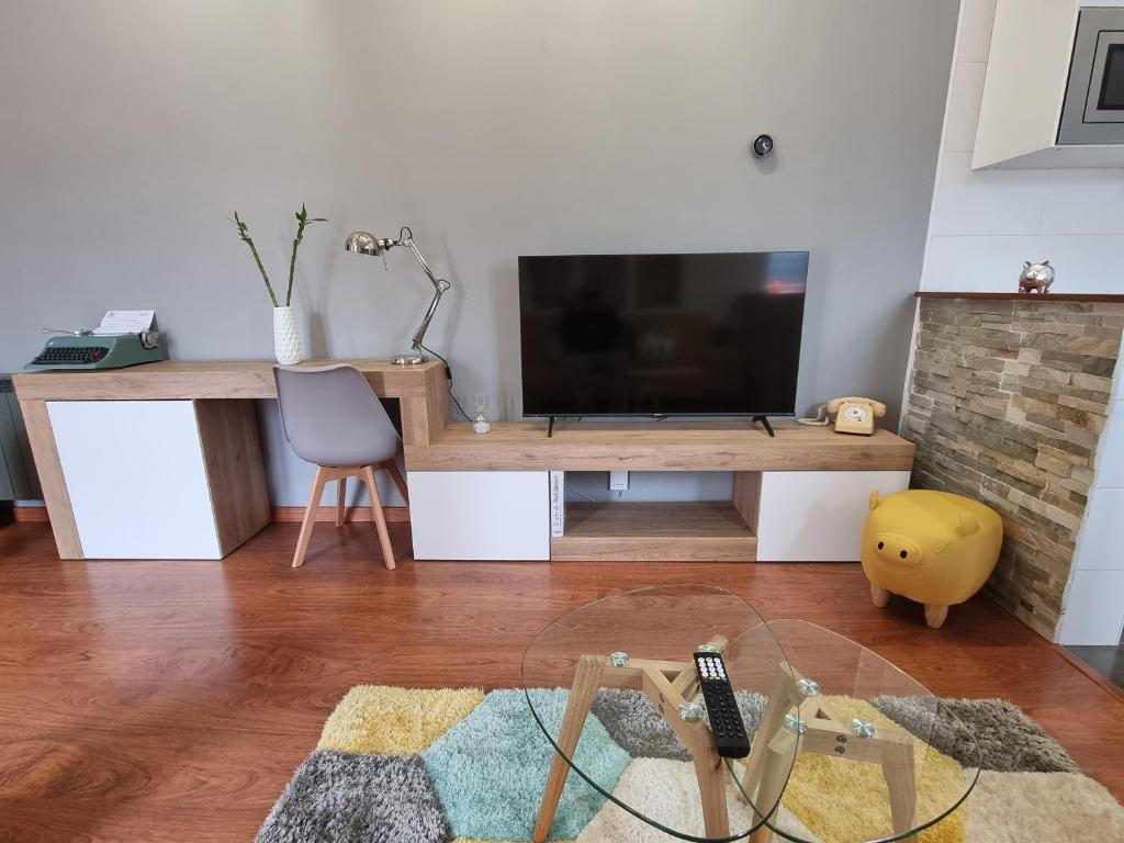 ein Wohnzimmer mit einem TV auf einem Holztisch in der Unterkunft Romántico apartamento con terraza y piscina in Villabáñez