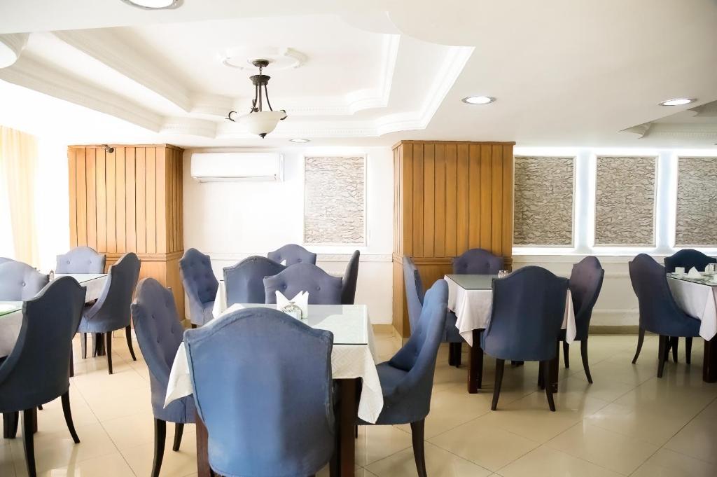 a dining room with blue chairs and tables and windows at Hotel Presidente Internacional in Guayaquil
