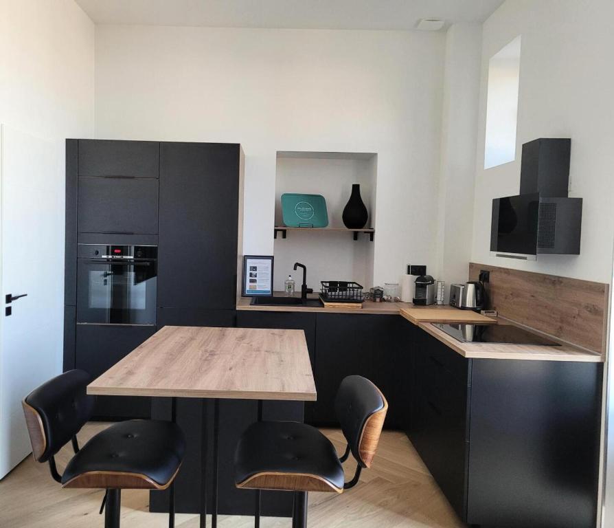 une cuisine avec une table en bois et des armoires noires dans l'établissement Résidence Le Bernascon - Chaleureux appartement dans ancien palace ! MAE-8154, à Aix-les-Bains